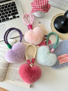 Macro detail of plush heart charms in pink, purple, and mint with braided ropes
