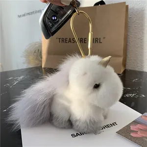 Close-up of white plush unicorn keychain with gold horn and metal horseshoe clasp