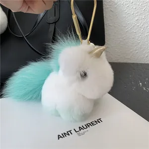 Detail of plush unicorn keychain with gold hook and soft faux fur on a leather bag