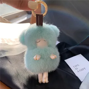 Cute light blue mink fur lamb keychain with golden ring on a silk background