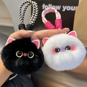 Detail view of plush cat keychains in black and white with fluffy texture and braided cords