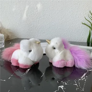 Detail of plush unicorn pendants with soft white fur and golden horns on a marble surface