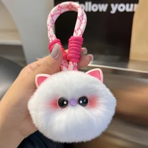 Close-up of a white plush cat keychain with fluffy fur and a woven pink lanyard strap