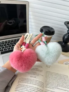 Detail of plush heart-shaped bag charms in pink and mint green with woven cotton rope