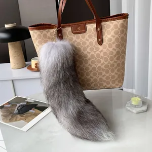 Long fluffy gray fox tail keychain made of faux fur attached to a stylish tote bag
