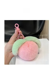 Detail of pink plush peach keychain with green leaves and pink clasp, approx 11cm size