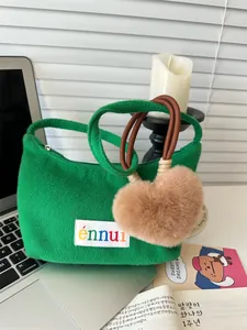 Close-up of green plush handbag featuring an ennui tag and brown heart fur charm