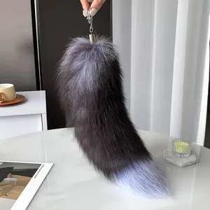 Pluffy faux fox tail charm in dark grey and lilac gradient on marble background