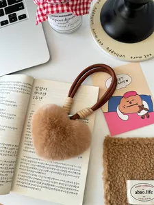 Close-up of caramel plush heart pendant with brown woven lanyard and soft fur texture