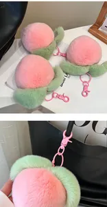 Close-up of plush peach keychain with soft pink fur and green leaf on a bag