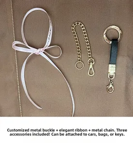 Détail du nœud rose, de la chaîne dorée et du charme en cuir pour porte-clés lion