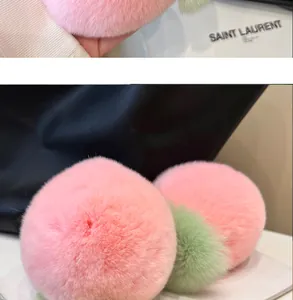 Detailed view of two soft pink plush peach charms with green leaves on a luxury handbag