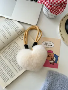 Detailed view of a soft cream faux fur heart-shaped charm with woven cord and boho accents