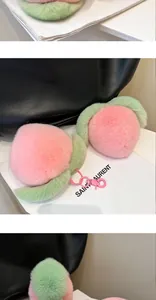 Close-up of plush peach keychains with soft pink faux fur and green leaf detail