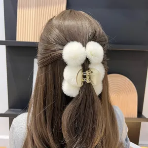 Close-up of white plush fur claw clip with large soft faux fur balls for women