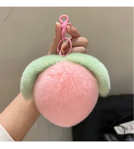 Detailed view of a soft pink plush peach keychain with green leaves and matching metal hook
