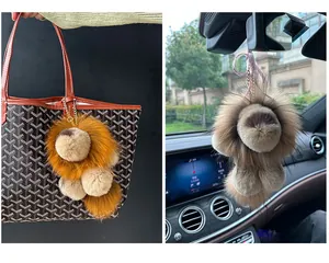 Détail d'un porte-clés lion en peluche avec chaîne dorée sur un sac et un rétroviseur