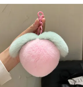 Close-up of a soft pink plush peach keychain with green leaves and a metal clasp