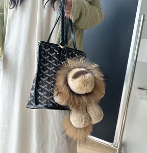 Détail d'un bijou de sac lion en peluche avec texture douce et lanière en cuir sur un sac