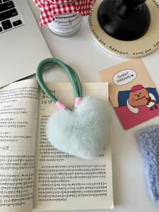 Close-up of fluffy mint green heart-shaped plush keychain on a woven cord handle