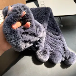 Macro detail of plush grey-blue rex rabbit fur scarf with soft pom-pom and thick texture