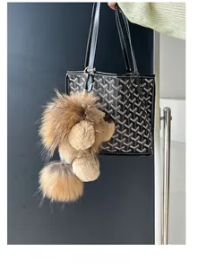 Détail d'un porte-clés lion en peluche douce avec fermoir doré sur un sac à main noir