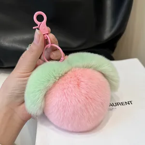 Cute pink plush peach keychain with green leaves and metal spring hook on a bag
