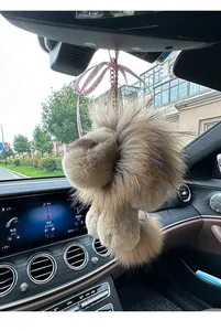 Détail d'un porte-clés lion en peluche de luxe suspendu au rétroviseur d'une voiture