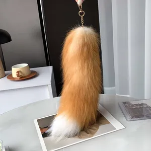 Fluffy red fox tail keychain with golden metal clasp on a stylish minimalist desk setup