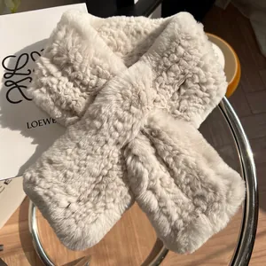 Texture détaillée d'une écharpe en peluche crème montrant la matière et le design croisé