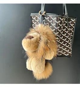 Porte-clés lion en peluche douce accroché à un sac à main de luxe en cuir noir