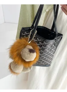 Détail d'un pendentif lion en peluche avec fourrure brune et chaîne dorée sur un sac