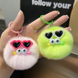 Close-up of fluffy plush ball keychains with heart sunglasses and pink green faux fur