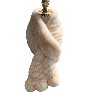 Creamy beige thick faux fur scarf with fluffy pom-poms on a gold-capped display mannequin