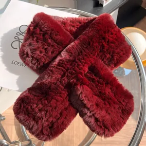 Gros plan d'une écharpe en peluche bordeaux avec un design croisé sur un présentoir