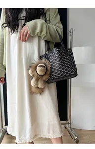 Détail d'un porte-clés lion en peluche sur un sac cabas noir avec motif à chevrons