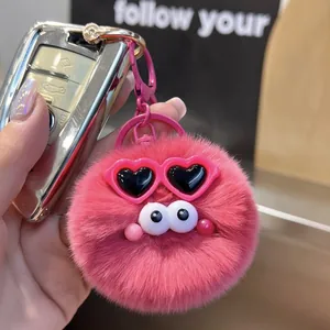 Close-up of pink fluffy pompom keychain with heart-shaped glasses and metal hook