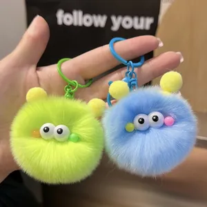 Detail of plush monster keychains in green and blue with soft fur and plastic hooks