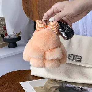 Dettaglio del portachiavi a forma di coniglio di peluche arancione con fiocco a quadri