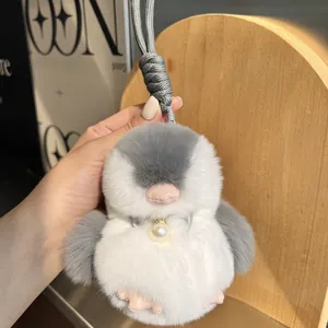 Portachiavi a forma di pinguino in peluche con fiocco di seta e perla in mano