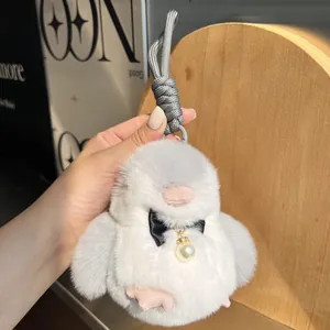 Dettaglio del portachiavi a pinguino di peluche grigio con fiocco nero e perla