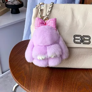Dettaglio portachiavi a forma di coniglio in pelliccia viola con fiocco su borsa beige