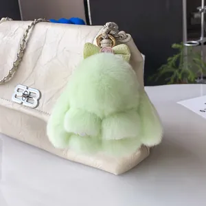 Gros plan d'un charme de lapin en peluche vert menthe avec nœud à pois sur un sac beige