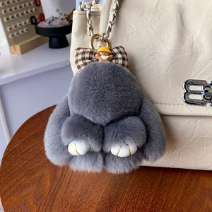 Grauer Plüsch-Hasen-Schlüsselanhänger mit Karo-Schleife an beige Lederhandtasche
