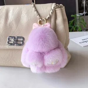 Porte-clés lapin en peluche violette avec nœud rose sur un sac à main beige élégant