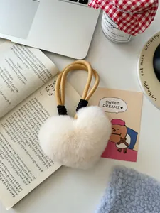 Detailopname van de hartvormige imitatiebont sleutelhanger in crème op een bureau-omgeving