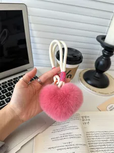 Detailopname van een roze pluche hart-sleutelhanger met gevlochten koord op een bureau