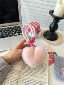 Detailweergave van een zachte roze hartvormige pluche sleutelhanger met gevlochten touw