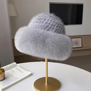 Graue Strickmütze mit flauschigem Kunstpelzrand auf einem goldenen Displayständer