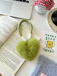 Detail van de lichtgroene pluche hart sleutelhanger met geweven koord op lifestyle-achtergrond